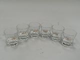 six verres de whisky posés sur une table blanche, sur fond blanc