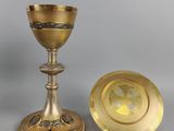 un calice et une assiette en laiton posés sur une table avec un fond gris