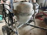 a cement mixer sitting in a garage next to other tools