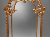 un miroir richement sculpté, avec un cadre doré sur fond gris