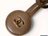 the brown leather keychain has a gold logo on it