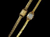 a gold watch and a gold bracelet on a black background