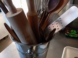 many wooden utensils in a bucket on the counter