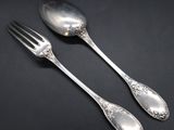 two silver spoons and a fork on a black surface