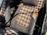two seats in the back of a car with a plaid seat cover