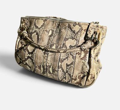 le sac à main en peau de serpent est posé sur une surface blanche