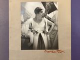 an old photo of a woman in a white dress is hanging on a purple wall