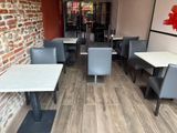 tables and chairs in a restaurant with a brick wall in the background