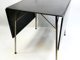une table noire à plateau rabattable sur fond blanc