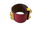 a close up of a red bracelet with gold spikes on it