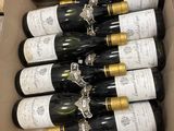 six bouteilles de vin dans un carton sur une table