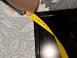 someone is measuring the width of a television screen with a yellow tape