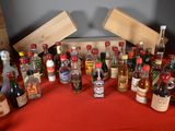 many bottles of alcohol sitting on a table with a red table cloth