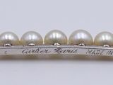 a close up of a bracelet with pearls on a white surface