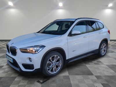 un SUV BMW blanc garé sur un sol à damier dans un garage