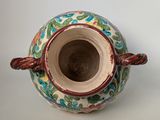 a small vase with a handle on a white table