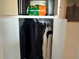 a closet with clothes hanging on it in the corner of a room