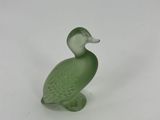 green glass duck figurine sitting on a white surface