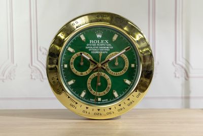 a gold clock with a green face on a wooden table