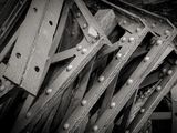 black and white photograph of a pile of wooden planks with rivets