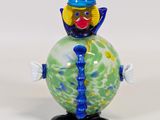 une figurine en verre représentant un clown avec un haut-de-forme et une cravate