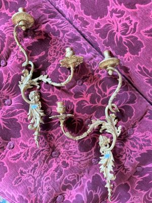 pair of antique brass wall sconces on a purple floral background