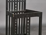 une chaise noire avec une assise en bois posée sur un sol en béton
