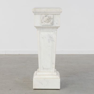 un socle en marbre blanc surmonté d'une horloge