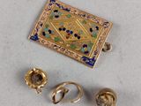 three pieces of gold and enamel jewelry on a white surface