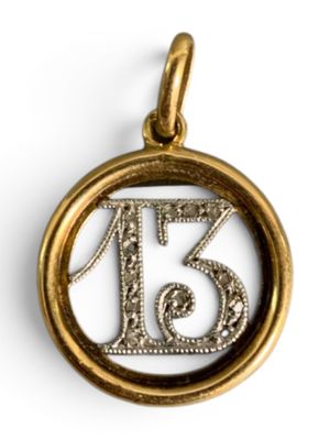 a close up of a gold pendant with the number thirteen on it
