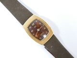une image représentant une montre avec un bracelet en cuir marron sur un fond blanc