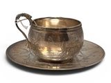 an antique silver cup and saucer on a saucer
