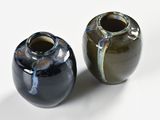 two vases sitting next to each other on a white surface