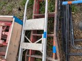 a pile of old chairs and ladders sitting on the ground