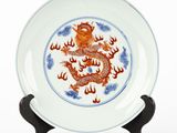 une assiette ornée d'un dragon, posée sur un socle