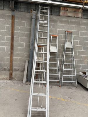 several ladders are lined up against a wall in a warehouse