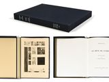 an open book sitting on top of a white table next to a black book