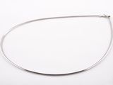 gros plan d'un collier en argent sur une surface blanche