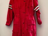 un imperméable rouge posé sur un mannequin, devant un mur blanc