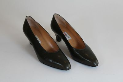 une paire d'escarpins en cuir noir à bout pointu posés sur une surface blanche