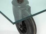 a glass table with a metal caste and a glass top