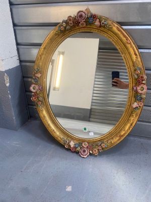 un miroir posé par terre près d'un mur
