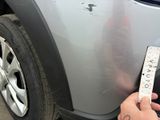 someone is holding a measuring tape to measure the front bumper of a car