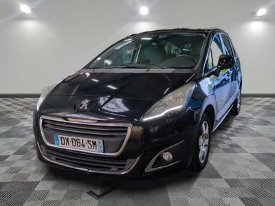 La petite voiture noire est garée dans le garage, sur le sol à damier.