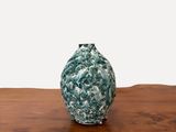 un petit vase vert posé sur une table en bois