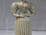 une statue représentant une femme en robe, posée sur une table