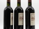 three bottles of wine are lined up on a white surface