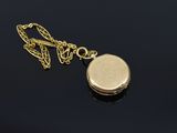 a close up of a gold locke with a chain on a black surface