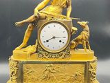 a gold clock with a statue of a woman sitting on top of it