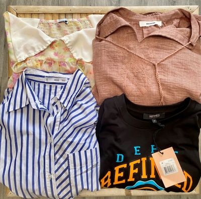 three shirts and a shirt hang on a clothes rack on a wooden floor